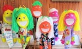 Colorful puppets with bright hairstyles and playful expressions stand against a wooden backdrop, showcasing creativity and fun for children's activities.