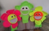Colorful flower puppets in bright neon shades of pink, green, and orange, showcasing cheerful faces, ideal for children's entertainment or educational activities.
